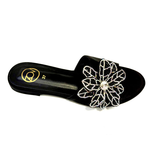 Black sandal with a decorative flower and pearl detail on a white background