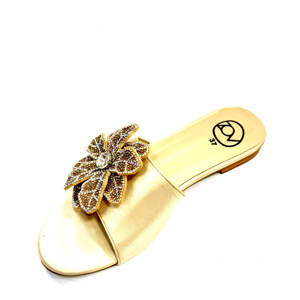 Gold sandal with a decorative flower on a white background
