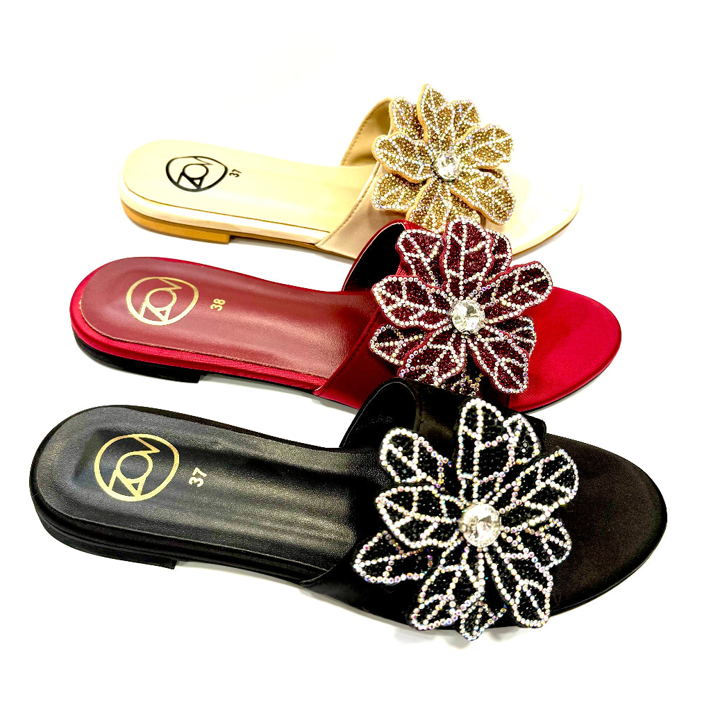 Three sandals with floral embellishments on a white background